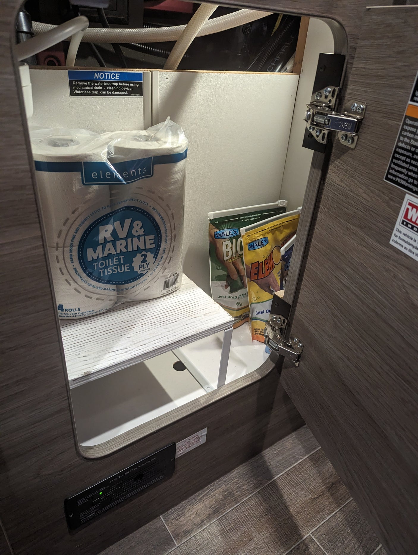 RV rental cabinet: RV toilet tissue, Walex tank treatments, and a propane alarm for essential RV use and safety.