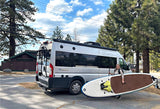Woman with paddleboard next to her RV rental, ready for adventure at Zephyr Cove Resort.