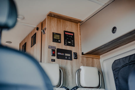 RV rental interior: A detailed view of the Winnebago control panel with solar and tank heater systems.