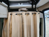 Inside an RV rental, featuring beige privacy curtains, overhead storage labeled 'Pop-top Ladder' & 'Window Covers'.