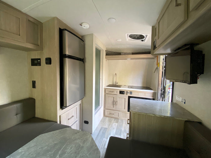 RV rental interior: A bright, functional space with a compact kitchen (fridge, sink), dinette seating, and overhead storage.