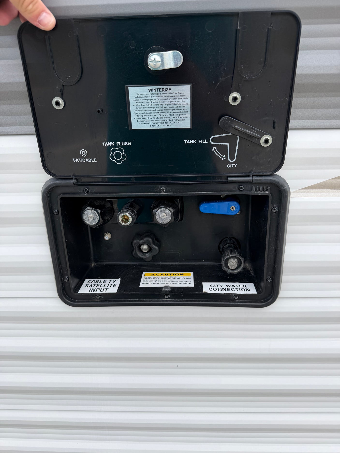 RV rental utility panel: connections for city water, tank fill/flush, winterization, and cable/satellite inputs.