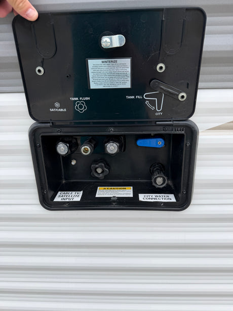 RV rental utility panel: connections for city water, tank fill/flush, winterization, and cable/satellite inputs.