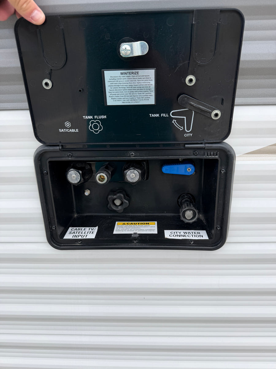 RV rental utility panel: connections for city water, tank fill/flush, winterization, and cable/satellite inputs.