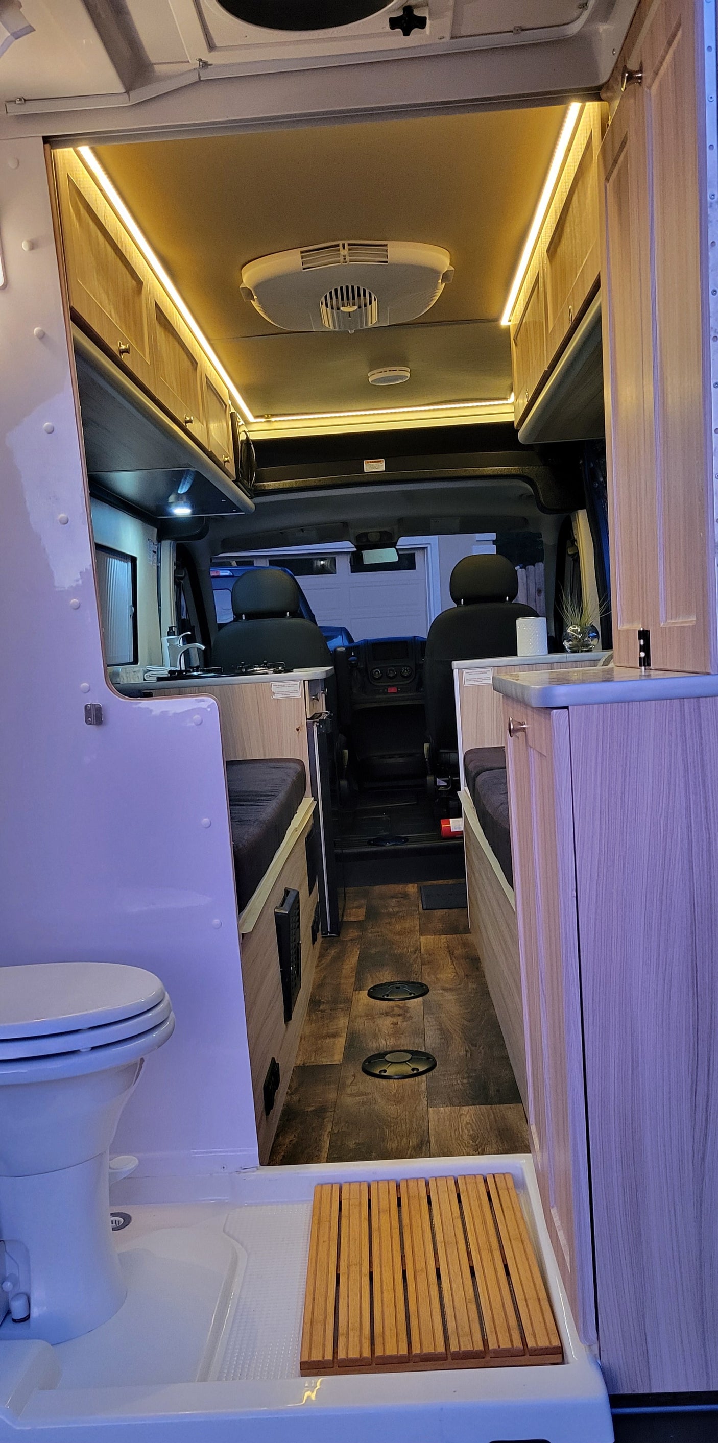 Bright rv rental interior: compact wet bath, full kitchenette, and cozy living space with smart storage & LED lighting.