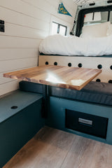 RV rental's modern camper interior features shiplap, bed, wooden table, and Dometic fridge.