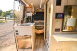 Experience comfort in this RV rental! Its camper van interior features a modern kitchen, cozy bed, and outdoor view.