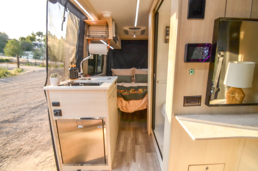 Experience comfort in this RV rental! Its camper van interior features a modern kitchen, cozy bed, and outdoor view.