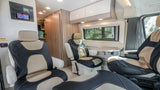 RV rental interior: Comfortable black and tan seating, control panel, fold-out table, and cabinet storage in a modern camper van.
