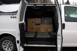 Open doors of an rv rental camper van reveal a practical custom interior with wood storage, fridge, and heater.