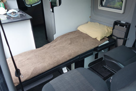 Cozy rv rental interior: compact sleeping area, kitchenette, and portable table for a comfortable road trip.