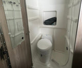 Inside an RV rental, this compact wet bath features a toilet, shower, and a mirror on the door.