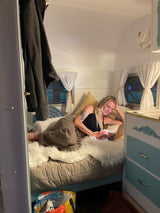 Woman relaxing on bed with laptop in a cozy RV rental. Perfect for a comfortable travel or remote work experience.