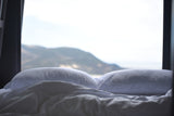 Cozy bed with white linens and a picturesque mountain view from your RV rental.