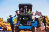 Family and kids set up their rv rental Jeep for desert camping. Pillows are passed into the rooftop tent for an outdoor adventure.