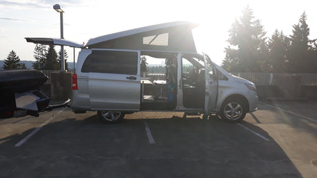Silver Mercedes Metris pop-top camper van RV rental, open and ready for adventure with its rear trailer.
