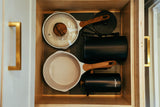 Compact kitchen storage in an RV rental: organized pots, pans, and small appliances in a wood drawer.