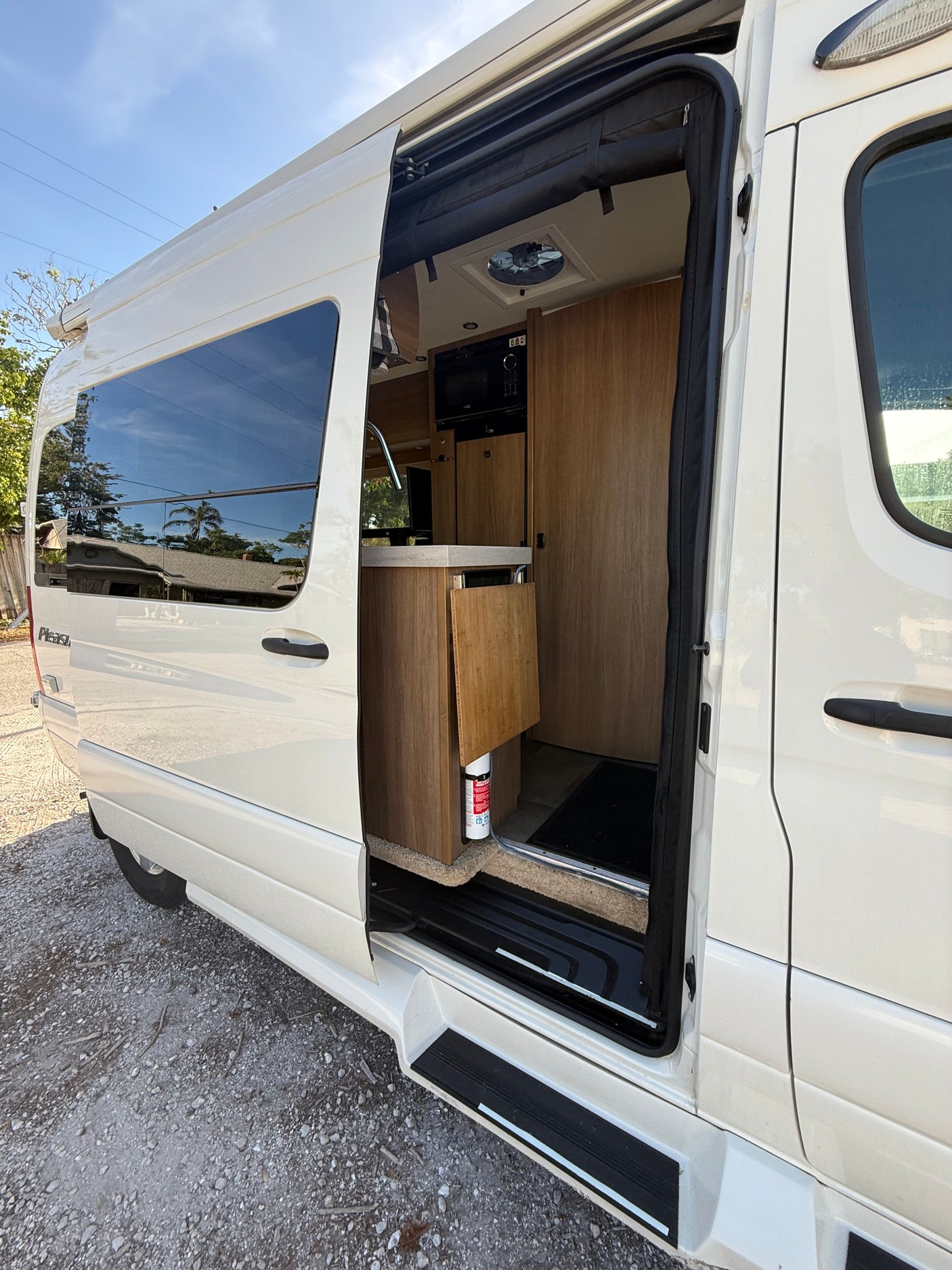 Pleasure-Way RV rental with open side door showing interior kitchenette, ready for your next trip.