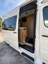 Pleasure-Way RV rental with open side door showing interior kitchenette, ready for your next trip.