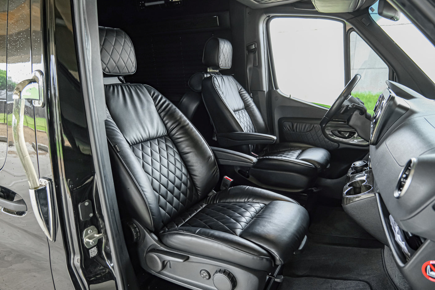 Luxurious black leather interior of a custom van, featuring quilted seats and modern dashboard, ideal for rv rental or executive travel.