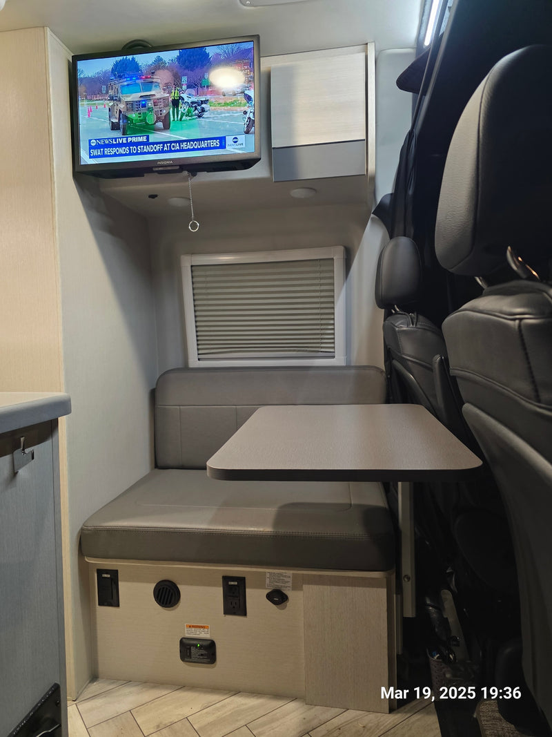 and light-toned storage cabinets above tinted windows.|Cozy RV rental interior with grey bed — photo 9