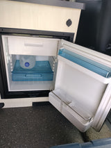This **rv rental** features a compact, open refrigerator with a water jug inside and built-in USB charging port.