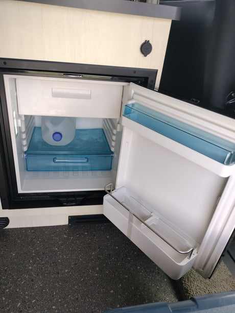 This **rv rental** features a compact, open refrigerator with a water jug inside and built-in USB charging port.