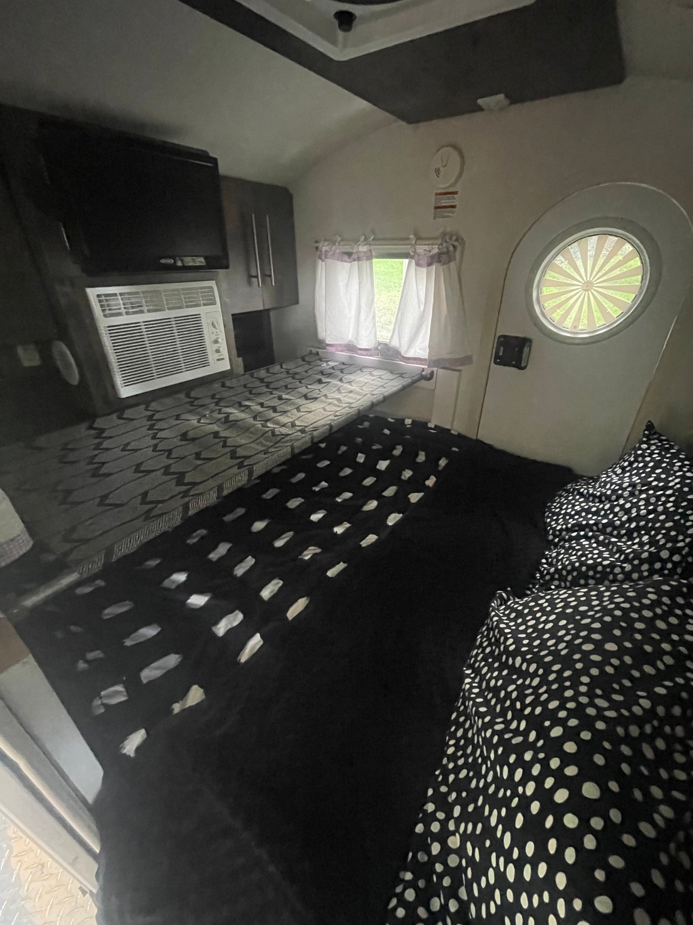 Compact RV rental interior featuring a bunk bed, main sleeping area, TV, and AC unit, ideal for travel.