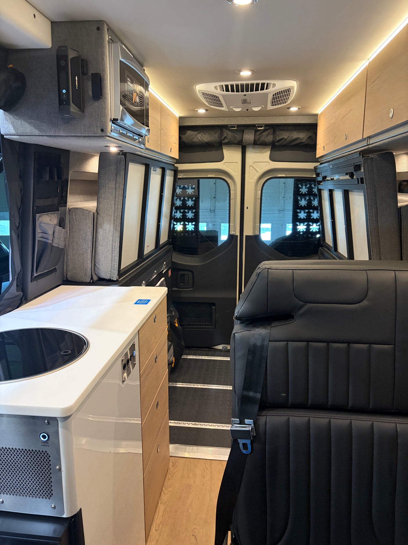 Explore this modern RV rental interior featuring a kitchen, microwave, AC, overhead storage, and passenger seating.