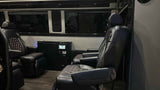 Luxury RV rental interior with plush captain's chairs, modern controls, and dark wood-look floor for comfortable travel.
