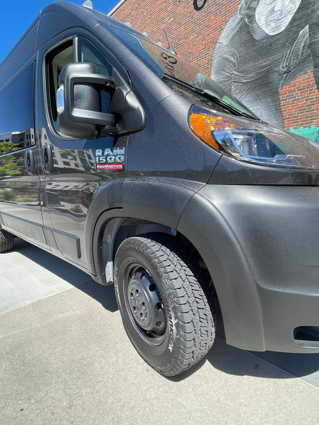 Close-up of a dark gray Ram ProMaster van, ideal for RV rental adventures. Features rugged tires.