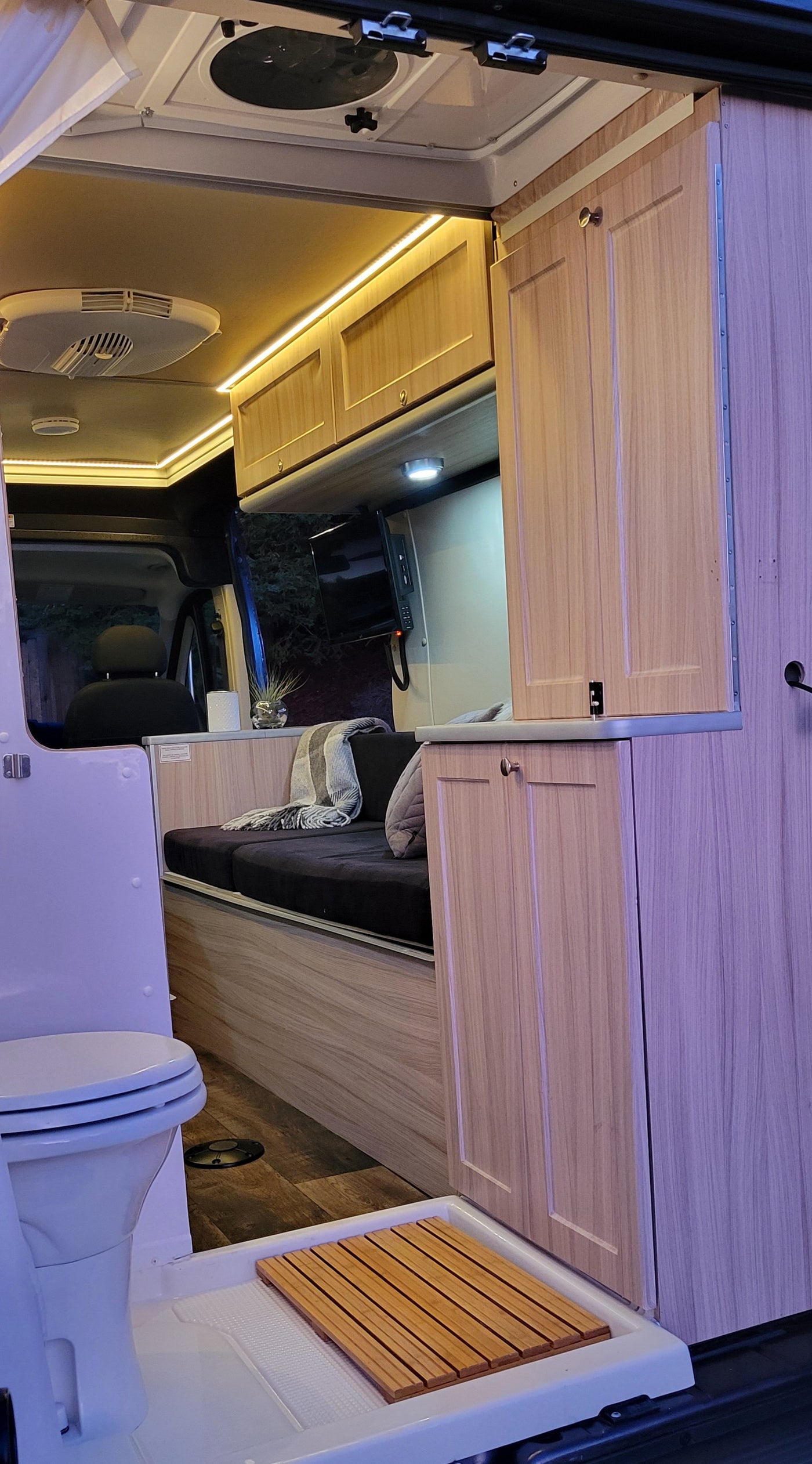Inside a bright rv rental, featuring a compact wet bath with toilet and shower, sleek cabinetry, and cozy seating. — photo 9