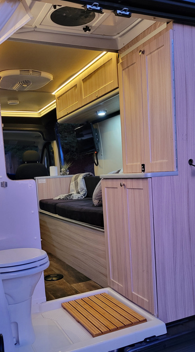 Inside a bright rv rental, featuring a compact wet bath with toilet and shower, sleek cabinetry, and cozy seating. — photo 9