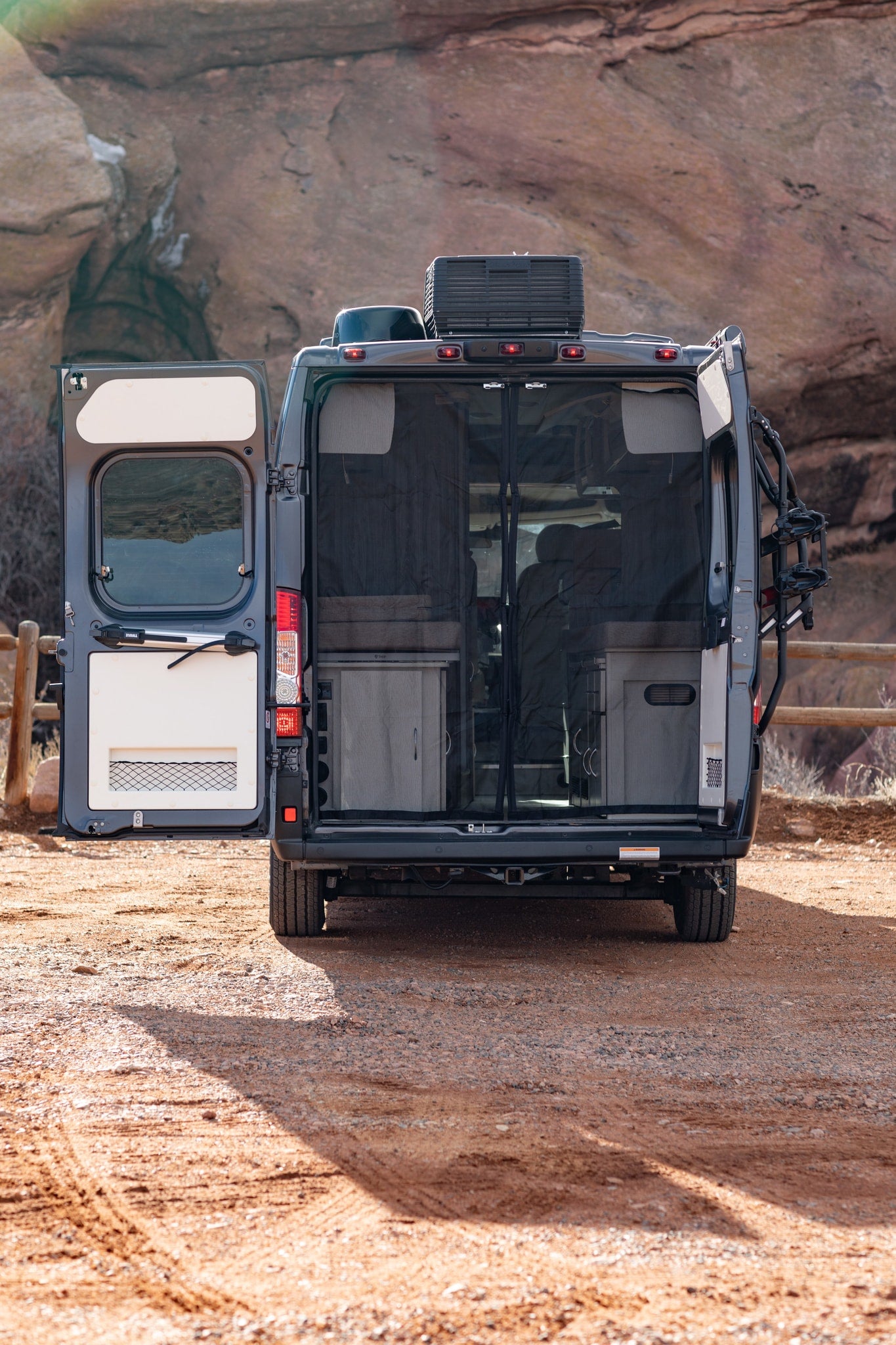  backed by rock formations.|Dark gray Ram Tellaro camper van with pop-top roof for rv rental — photo 12