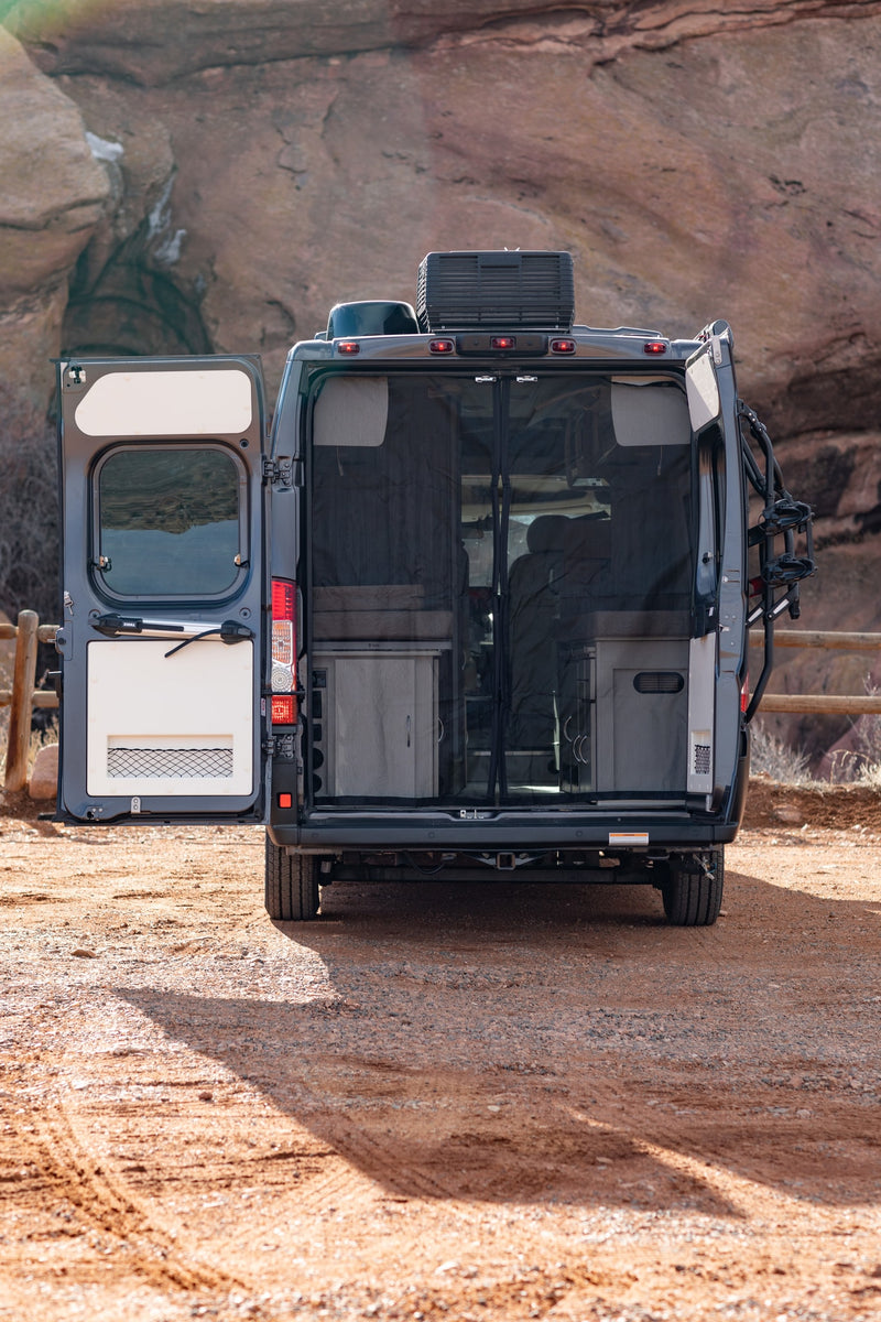  backed by rock formations.|Dark gray Ram Tellaro camper van with pop-top roof for rv rental — photo 12