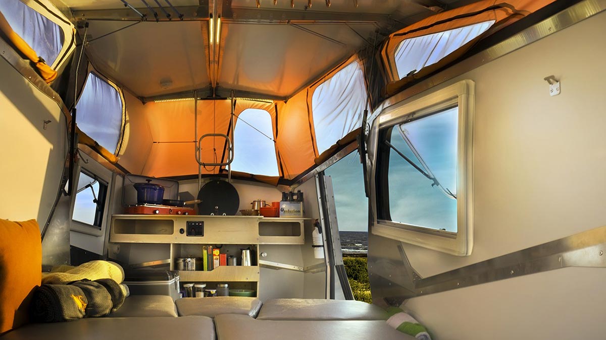  parked at a rustic campsite among trees.|This RV rental offers convenient kitchen amenities — photo 3