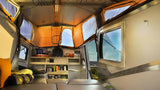 Explore comfort in this RV rental's cozy interior, featuring a functional kitchen and stunning outdoor views.