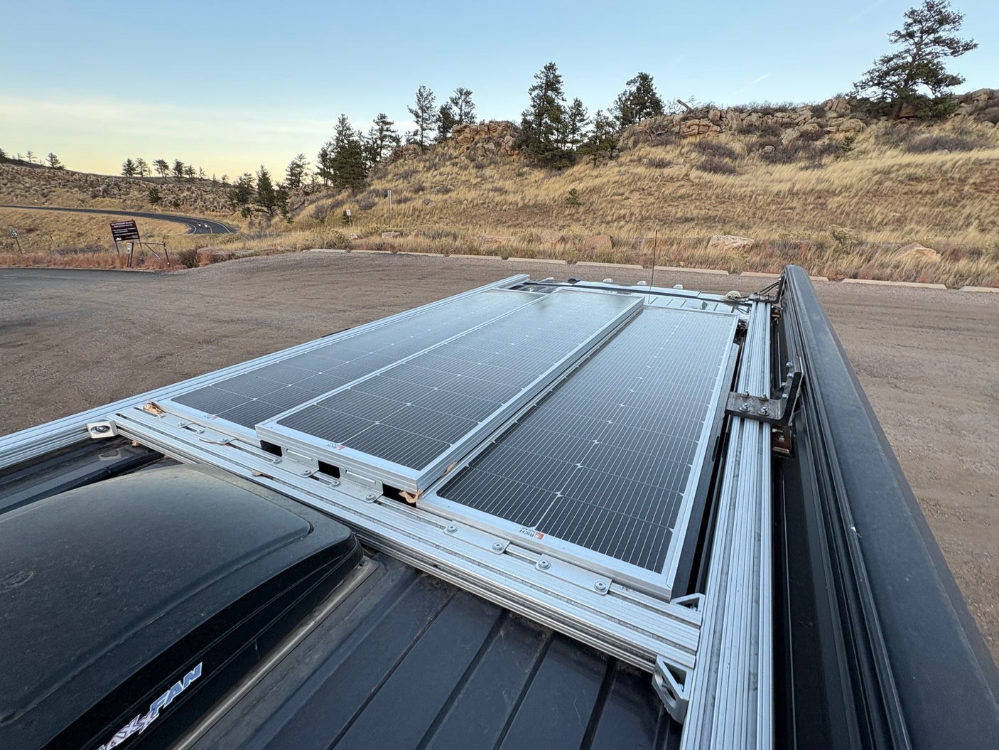 Rooftop solar panels on an rv rental van, showcasing renewable energy for off-grid adventures in a scenic, hilly landscape.