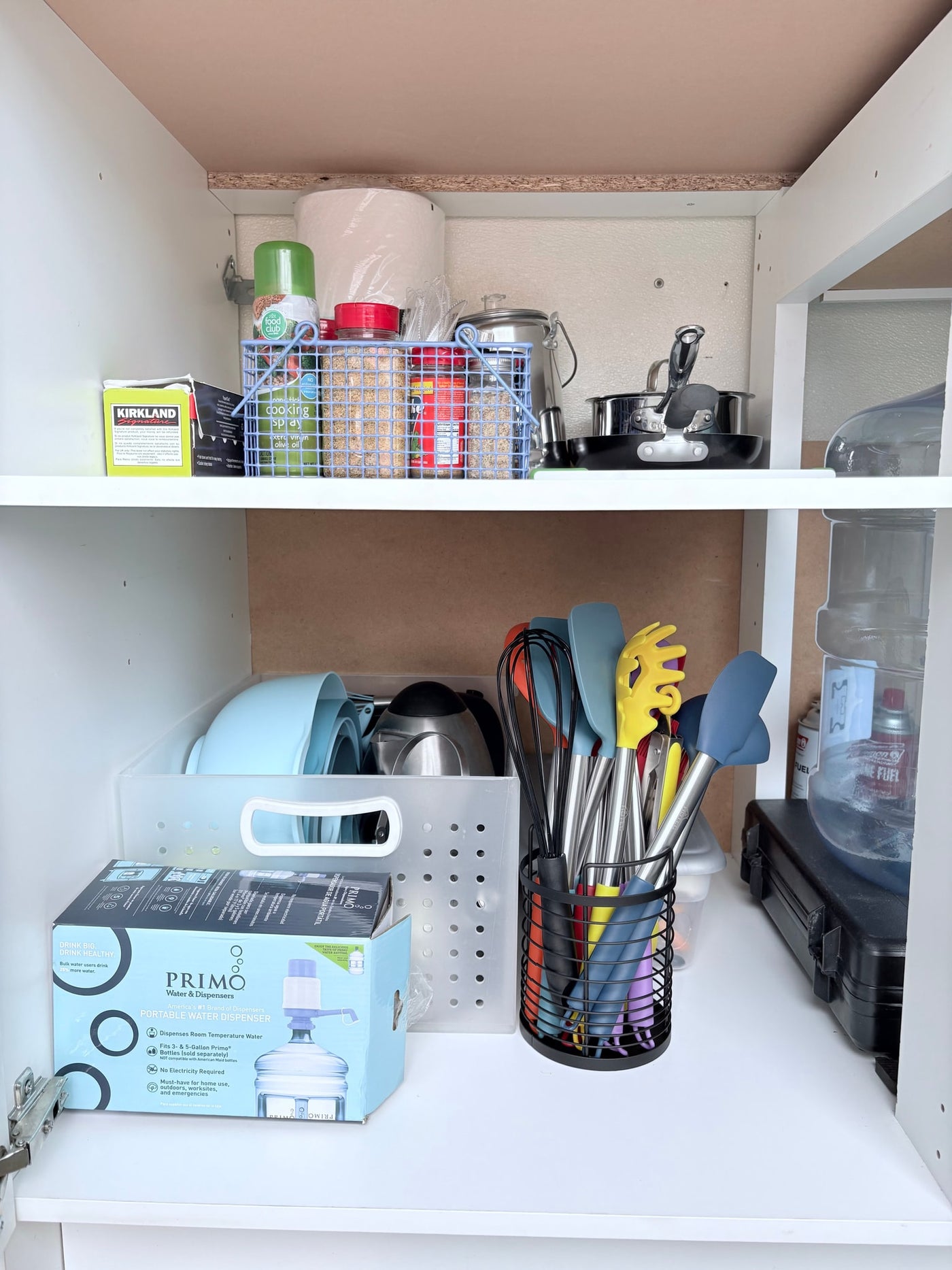 RV rental supplies: Cabinet organized with kitchen utensils, spices, cooking spray, and a portable water dispenser for travel. — photo 12