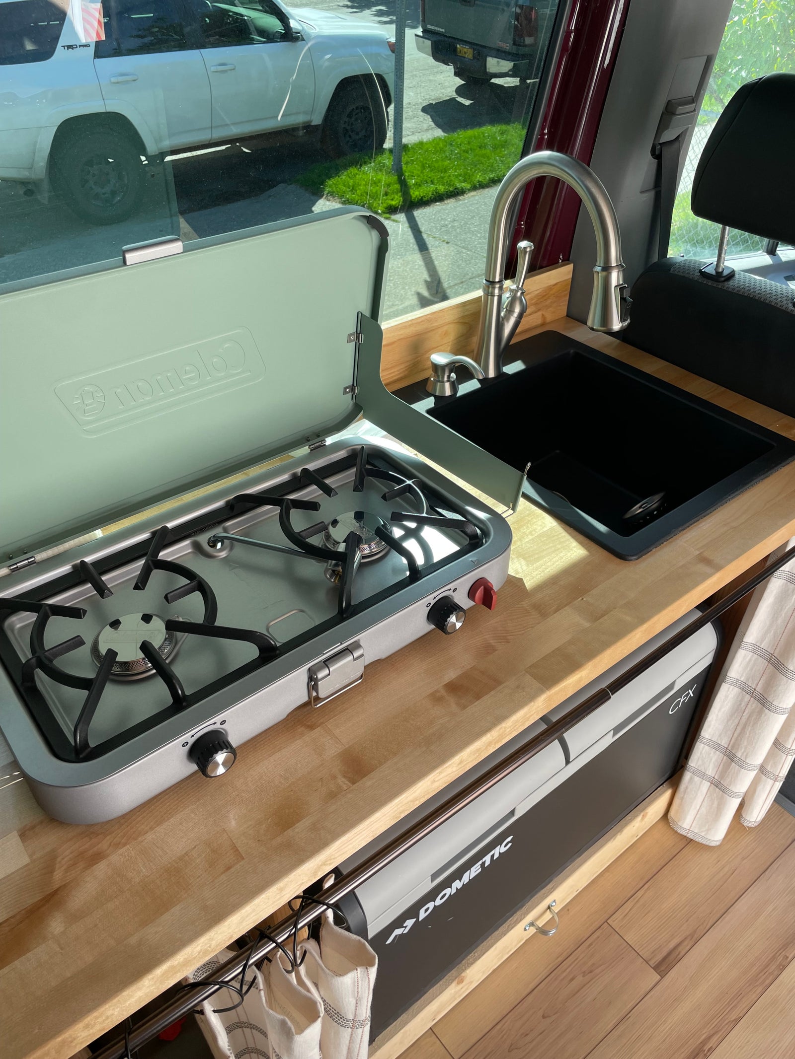 RV rental interior: A compact kitchen setup with a Coleman stove, black sink, and Dometic CFX cooler.