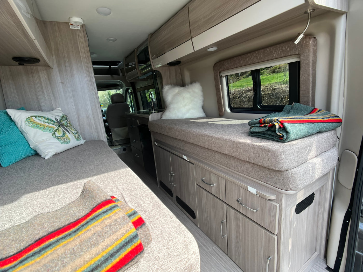 Spacious RV rental interior featuring comfortable seating/sleeping areas, a compact kitchen, and ample storage for travel. — photo 9