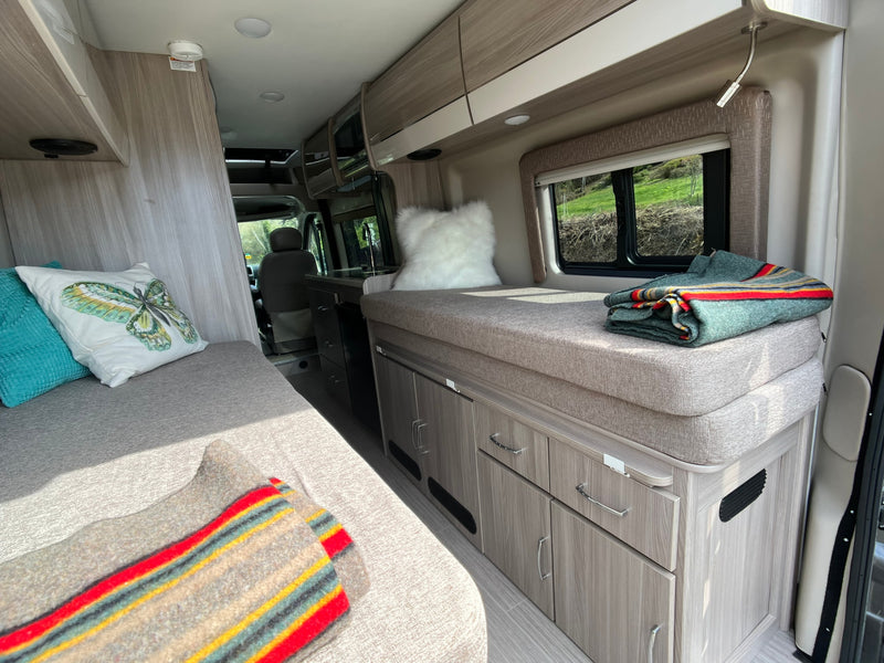 Spacious RV rental interior featuring comfortable seating/sleeping areas, a compact kitchen, and ample storage for travel. — photo 9