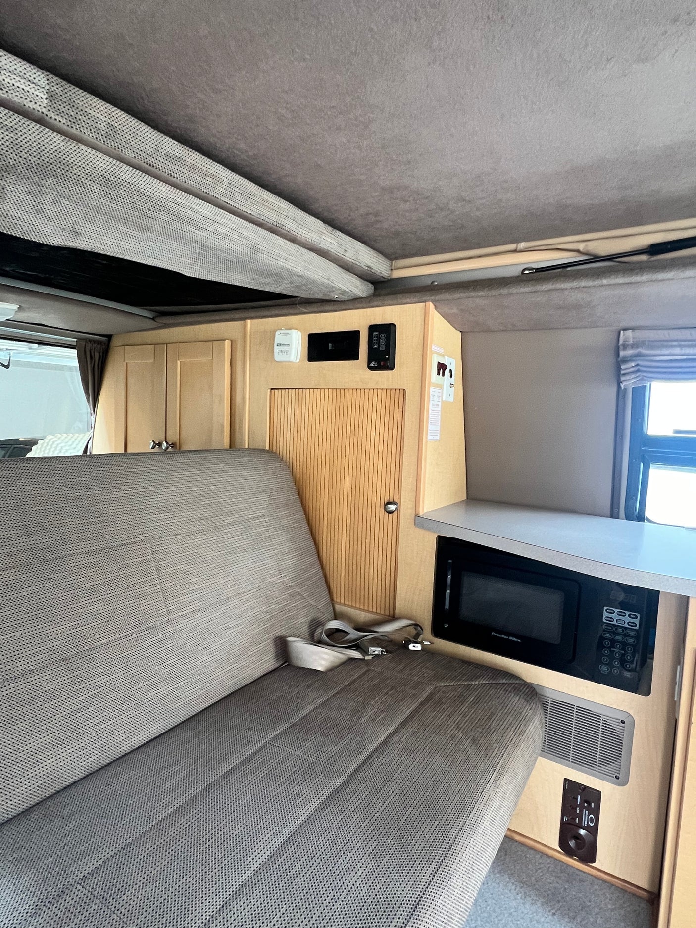 RV rental: Pop-up camper interior with bench seat, microwave, and wood storage. Functional living space.