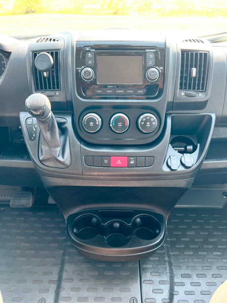 RV rental dashboard: detailed view of infotainment, climate controls, gear shift, and charging ports for convenience on the road.