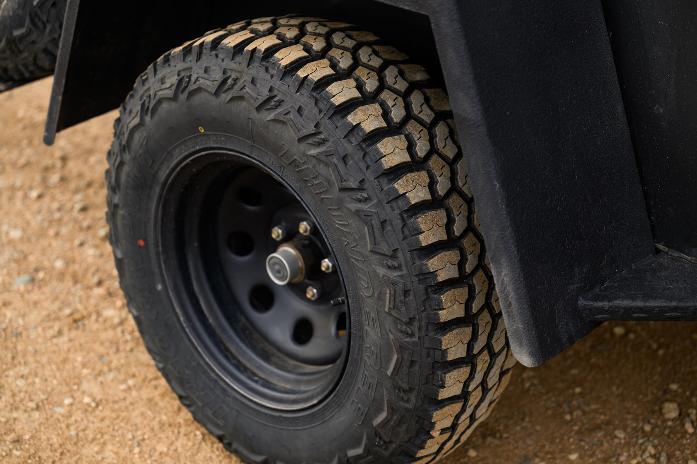 Rugged, dirty tire of an RV rental trailer, showcasing off-road readiness for adventure trips.