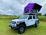 Explore with this white Jeep Wrangler RV rental featuring a vibrant purple rooftop tent, perfect for outdoor camping.