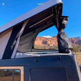 Inside an RV rental pop-top camper, revealing a breathtaking view of red rock mountains and snow-capped peaks.