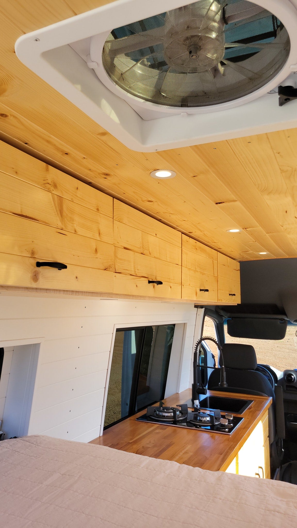  ready for your RV rental adventure. Parked on gravel.|RV rental storage: Light wood cabinet with rolled colorful blankets — photo 19