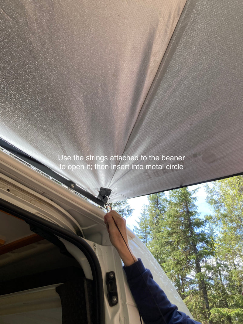 A hand attaches a sunshade to an RV rental, clipping a beaner into a metal circle for outdoor setup. — photo 18