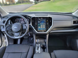 Subaru car interior: driver's view of dashboard, steering wheel, large infotainment screen (radio/climate), and gear shift. rv rental